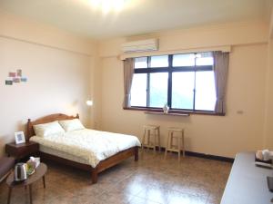 1 dormitorio con cama y ventana en Jiufen Hui Ming Homestay, en Jiufen