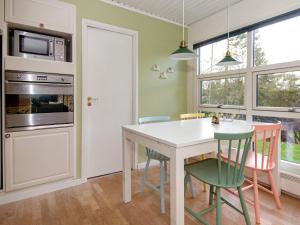 eine Küche mit einem Tisch, Stühlen und einer Mikrowelle in der Unterkunft 6 person holiday home in Knebel in Knebel