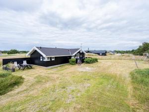 a black house in the middle of a field at Holiday home Vejers Strand XVIII in Vejers Strand