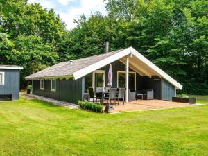 a green cottage with a porch and a deck at 6 person holiday home in Oksbøl-By Traum in Oksbøl