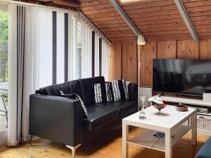 un sofá de cuero negro en una sala de estar con mesa en Holiday home Væggerløse CCXIII en Bøtø By