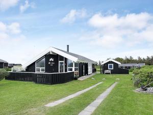 Two-Bedroom Holiday home in Hjørring 1 في لونستروب: منزل أبيض وأسود مع ساحة عشبية