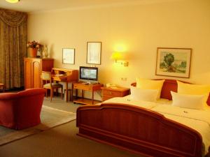 a bedroom with a large bed and a desk with a computer at Hotel Gasthof Vogelsang in Zellingen