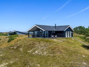 une maison noire au sommet d'une colline herbeuse dans l'établissement Holiday home Fanø CLXXIII, à Fanø