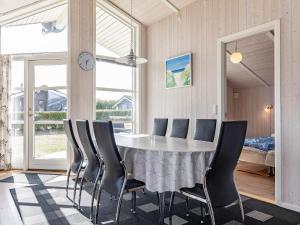 a dining room with a table with chairs and a clock at 6 person holiday home in Rudk bing in Spodsbjerg