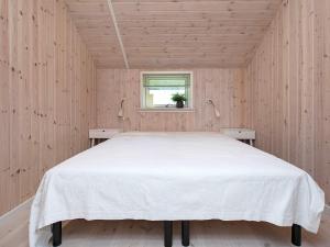 a bedroom with a white bed in a wooden room at 10 person holiday home in Stege in Stege