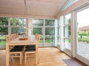 ein Esszimmer mit einem Tisch, Stühlen und Fenstern in der Unterkunft 6 person holiday home in Ulfborg in Ulfborg