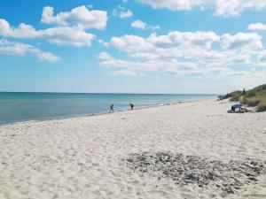 una playa de arena con gente caminando por el agua en 6 person holiday home in S by en Sæby