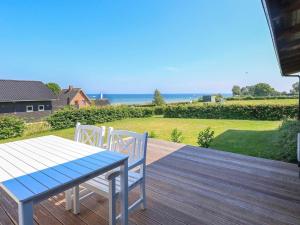 una terraza de madera con mesa y sillas. en 6 person holiday home in Hesselager, en Hesselager