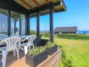 un patio con sillas blancas y una mesa con vistas al océano en 6 person holiday home in Hesselager, en Hesselager