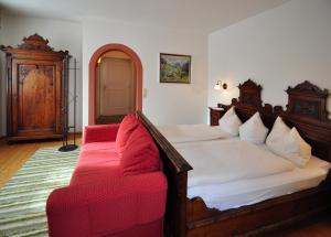 a bedroom with a bed and a red couch at Gasthof Lamm in Matrei am Brenner