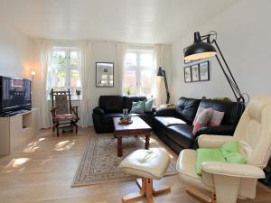 ロービュにある6 person holiday home in R dbyのリビングルーム(黒い革張りのソファ、椅子付)