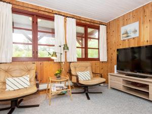 a living room with two chairs and a flat screen tv at 4 person holiday home in Toftlund in Toftlund