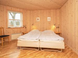 a bed in a room with wooden walls and a window at Holiday home Læsø XX in Læsø