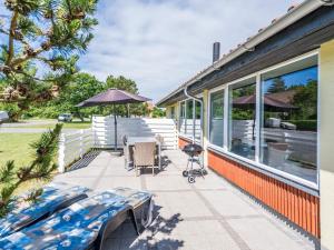 a patio with chairs and an umbrella on a house at Holiday home Nørre Nebel CXLII in Nørre Nebel