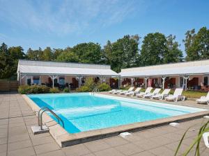 a swimming pool with chairs and a building at Holiday home Nexø XLI in Neksø