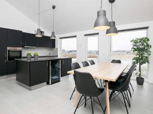 uma cozinha com uma mesa de madeira e armários pretos em 6 person holiday home in L kken em Lokken