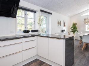 uma cozinha com armários brancos e uma sala de jantar em 8 person holiday home in Ringk bing em Ringkøbing