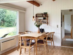 Bøtø ByにあるThree-Bedroom Holiday home in Væggerløse 39のダイニングルーム(木製テーブル、椅子付)