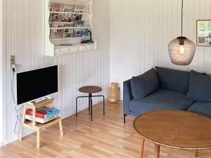 Bøtø ByにあるThree-Bedroom Holiday home in Væggerløse 39のリビングルーム(青いソファ、テーブル付)
