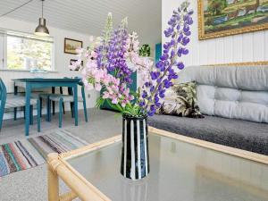 eine Vase mit lila Blumen auf einem Tisch im Wohnzimmer in der Unterkunft 5 person holiday home in Hj rring in Vester Vidstrup