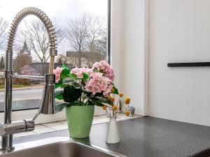 een vaas met roze bloemen op een aanrecht naast een wastafel bij 4 person holiday home in Toftlund in Toftlund