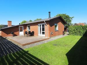 a brick house with a wooden deck in the yard at Holiday home Oksbøl LXIX in Oksbøl