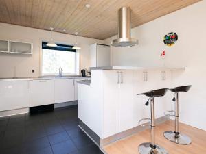 a kitchen with white cabinets and a sink and bar stools at Holiday home Oksbøl LXIX in Oksbøl