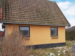 a yellow house with two windows in a field at 8 person holiday home in Hasle in Hasle