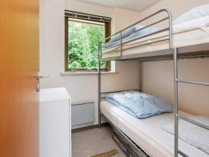a small bedroom with bunk beds and a window at Holiday home Glesborg XIX in Glesborg