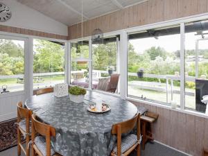 a dining room with a table and chairs and windows at 4 person holiday home in H jslev in Højslev