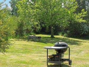 a grill in a field with a bench in the background at 4 person holiday home in H jslev in Højslev