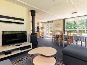 ein Wohnzimmer mit einem Sofa, einem TV und einem Tisch in der Unterkunft 6 person holiday home in Nibe in Nibe