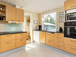 a large kitchen with wooden cabinets and appliances at 6 person holiday home in Nibe in Nibe