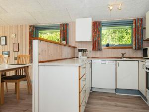 uma cozinha com electrodomésticos brancos e uma mesa e cadeiras em 6 person holiday home in B rkop em Egeskov