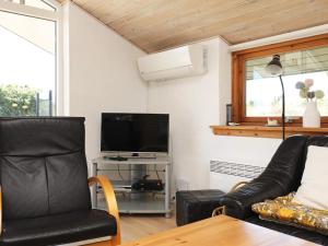 uma sala de estar com uma cadeira de couro preta e uma televisão em Three-Bedroom Holiday home in Ringkøbing 1 em Ringkøbing