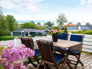 una mesa de madera y sillas en una terraza con flores en 6 person holiday home in Broager, en Broager