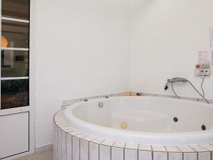 a white bathroom with a large tub in a room at 12 person holiday home in V ggerl se in Marielyst