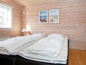 a bedroom with wooden walls and a bed with white sheets at Holiday home Egå II in Egå