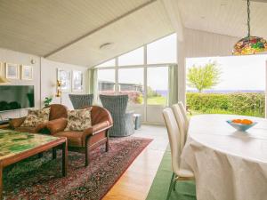 ein Wohnzimmer mit einem Tisch und Stühlen sowie einem großen Fenster in der Unterkunft Holiday home Brenderup Fyn IX in Bro