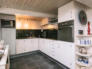 una cocina con armarios blancos y electrodomésticos negros en 4 person holiday home in Tranek r, en Tranekær
