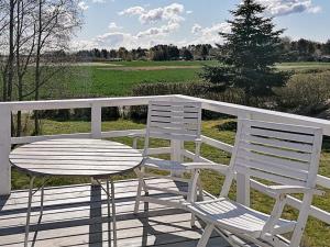 2 chaises blanches et une table sur une terrasse dans l'établissement 5 person holiday home in Vordingborg, à Vordingborg