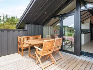 een houten tafel en stoelen op een terras bij Holiday home Ringkøbing LXI in Ringkøbing