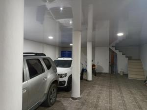 dos autos blancos estacionados en un estacionamiento en Hostal Apartamentos Delgado en Florencia