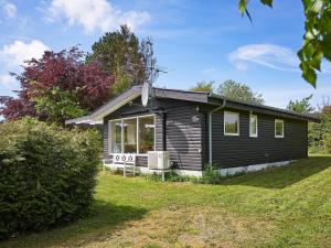 uma pequena casa negra num campo de relva em 6 person holiday home in Allinge em Allinge