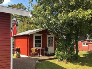 un cobertizo rojo con una mesa y sillas en una terraza en 4 person holiday home in Martofte, en Martofte