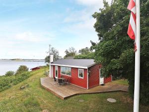 una casa roja con una terraza junto al agua en 4 person holiday home in Martofte, en Martofte