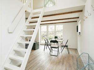 eine weiße Treppe in einem Zimmer mit einem Tisch und Stühlen in der Unterkunft 4 star holiday home in Skagen in Skagen