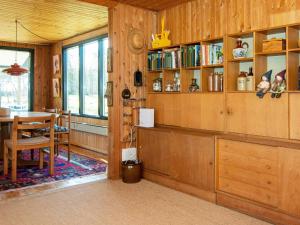 ein Esszimmer mit Holzwänden, einem Tisch und Regalen in der Unterkunft 6 person holiday home in Ulfborg in Ulfborg