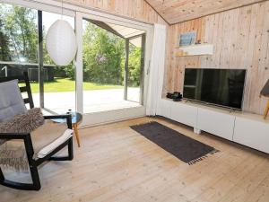 sala de estar con TV de pantalla plana y silla en Holiday home Hadsund II, en Hadsund